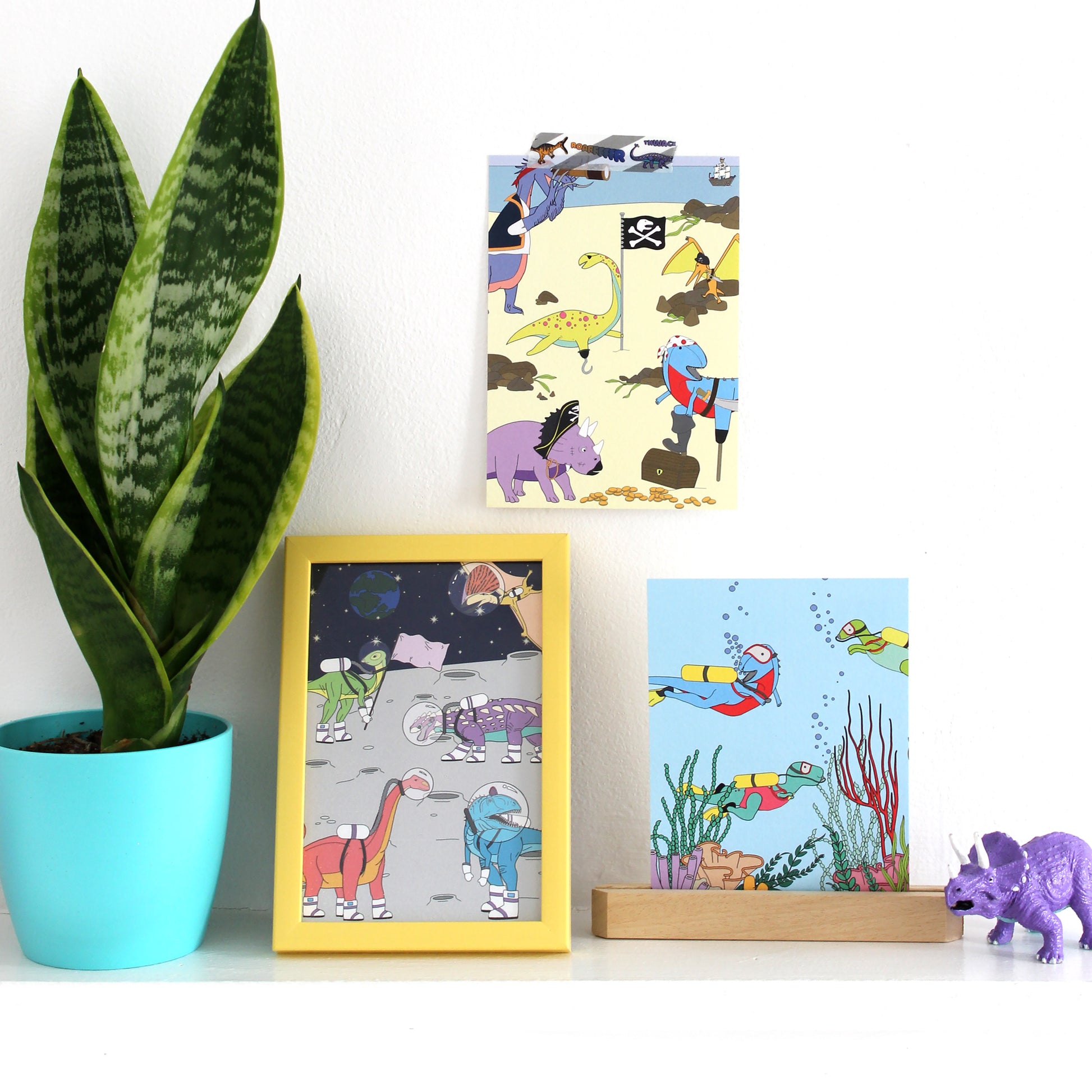3 dinosaur postcards displayed on a shelf