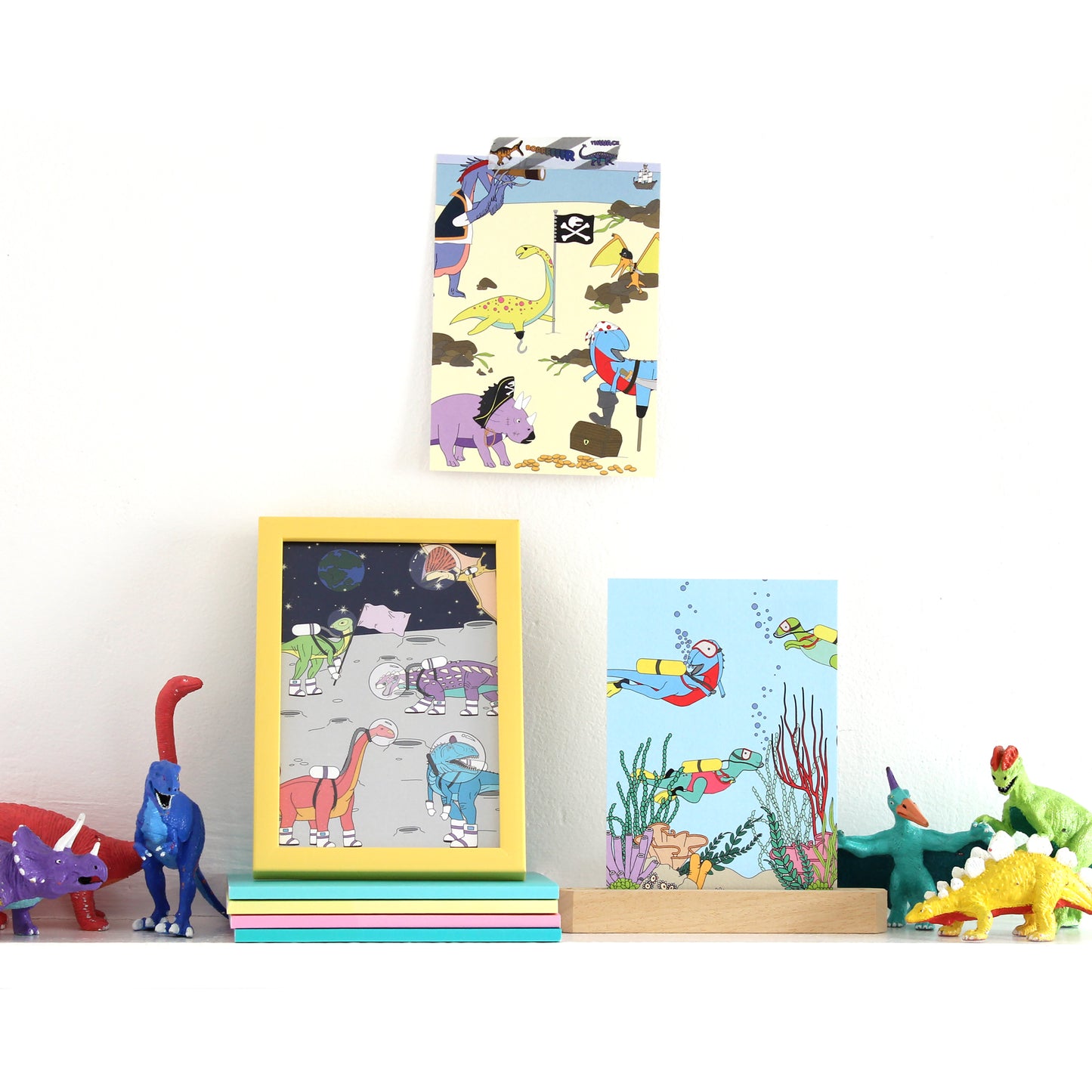 3 dinosaur postcards on a shelf with dinosaur figurines