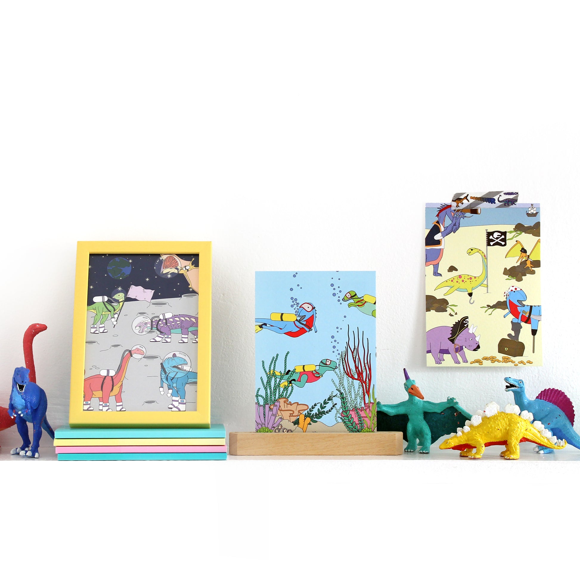 3 dinosaur postcards on a shelf with dinosaur figurines