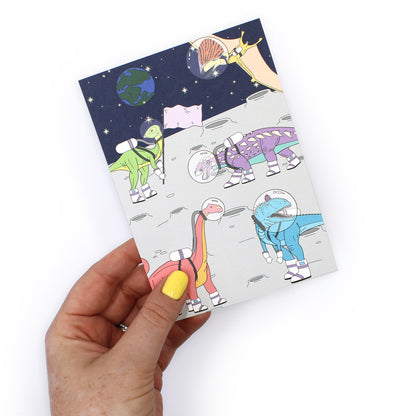 space dinosaur postcard held by a hand