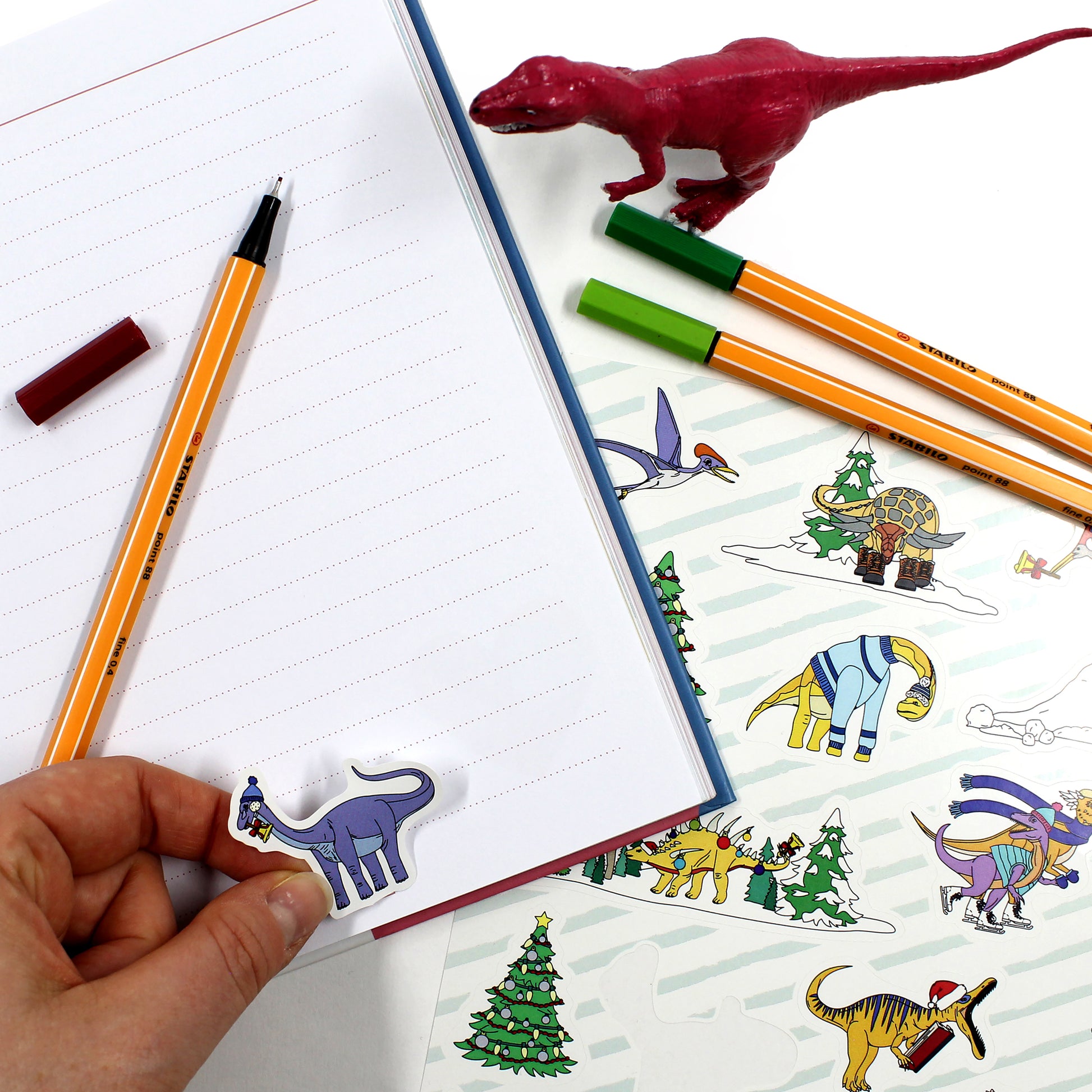 dinosaur Christmas stickers on a notebook with pens