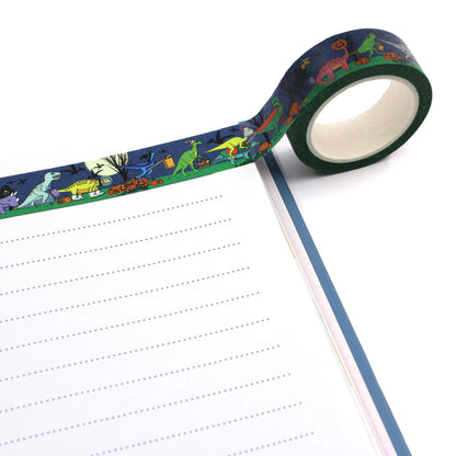 A roll of Halloween dinosaur washi tape rolled out on the top of a notebook