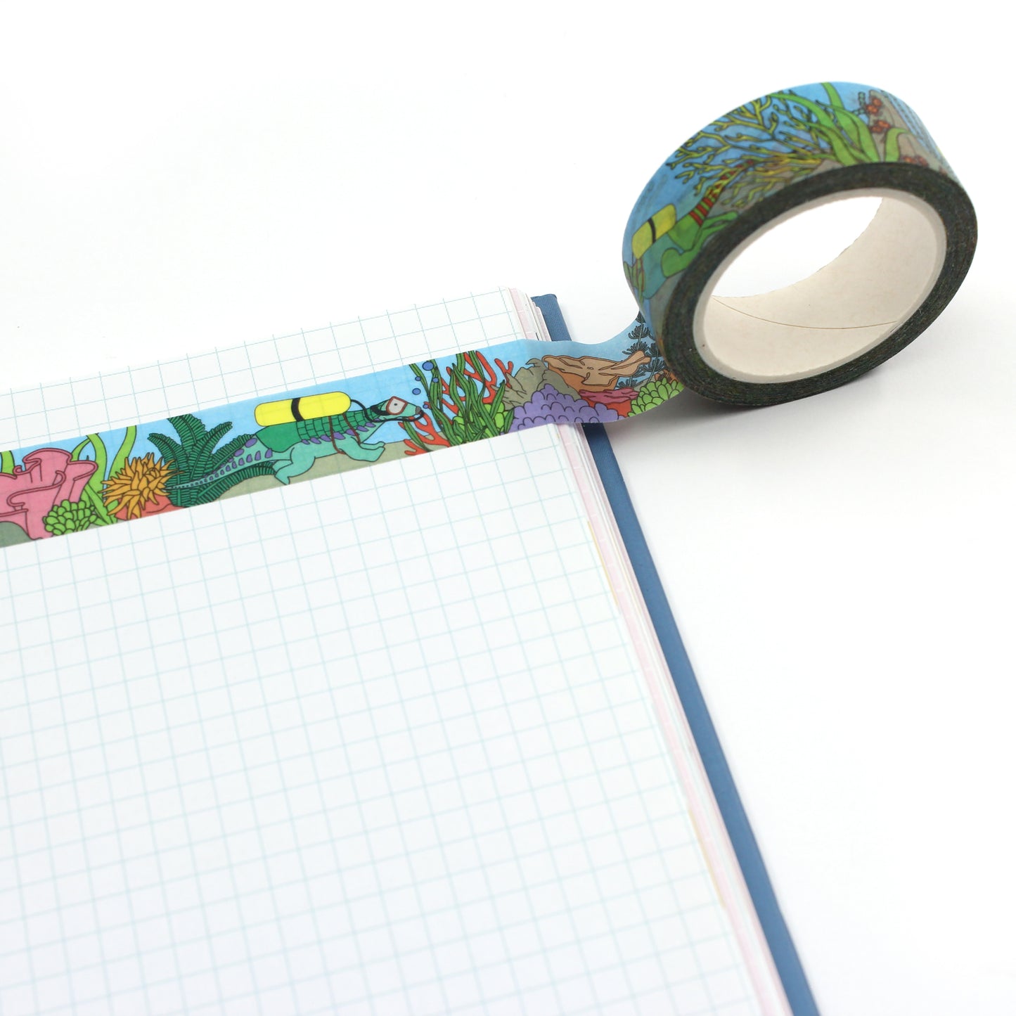 A roll of under the sea dinosaur washi tape along the top of a notebook
