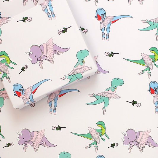 a sheet of ballet dinosaur wrapping paper with a box on top that is also wrapped in the same paper