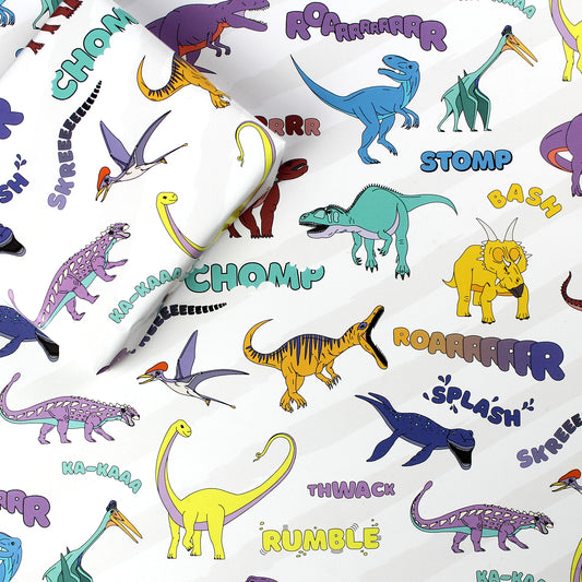 a sheet of dinosaur words wrapping paper with a box on top that is also wrapped in the same paper
