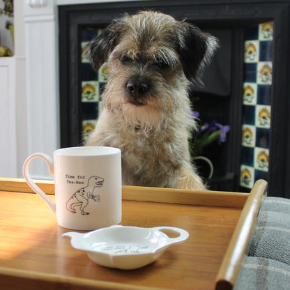 Time for Tea-Rex Mug on a wooden tray with a teabag tidy. There is a border terrier looking at the mug and a fireplace in the background